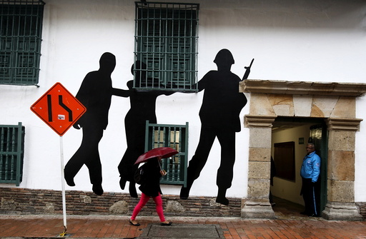 Citizens walk in front of a mural representing victims and missing people near the rebuilt Justice Palace in Bogota