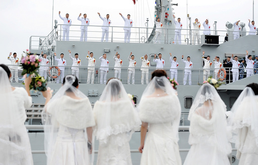Navy personnel of People's Liberation Army (PLA) wave at their brides during a mass wedding at a military base in Zhoushan