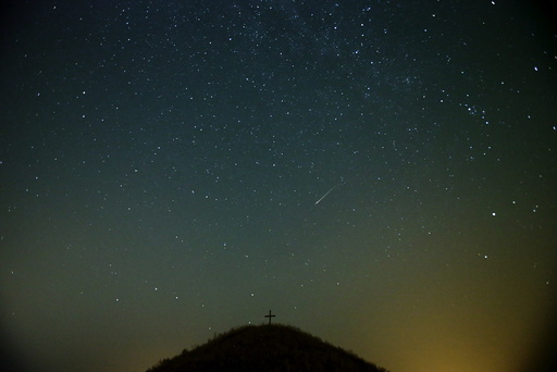 A meteor streaks across the sky over Leeberg hill during the Perseid meteor shower near Grossmugl