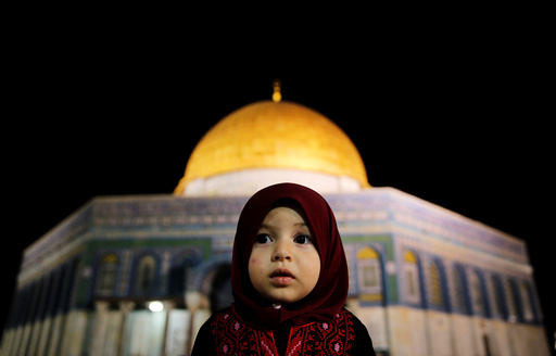 A Palestinian girl prays in front of the Dome of the Rock in Jerusalem's Old City during the holy month of Ramadan