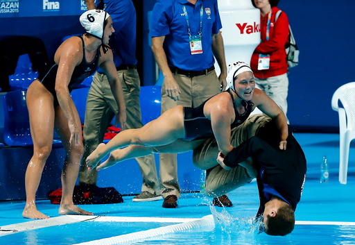 U.S. players push head coach Adam Krikorian into the pool after they defeated the Netherlands in their women's water polo gold medal match during the Aquatics World Championships in Kazan