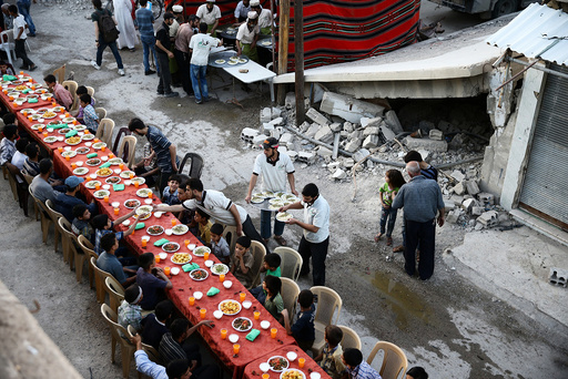 People gather for Iftar amidst damaged buildings during the holy month of Ramadan in the rebel held besieged Douma neighbourhood