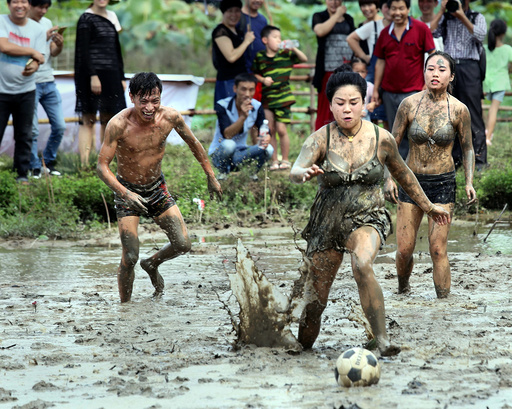 People fight for the ball as they take part in a mud football match in Jinhua