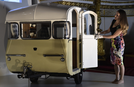 Curator of Royal Collection Trust Reynolds poses with a miniature caravan at Buckingham Palace in central London