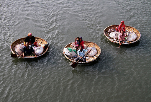 Fishermen paddle their boats as they carry their family members in the waters of Vembanad Lake in Kochi