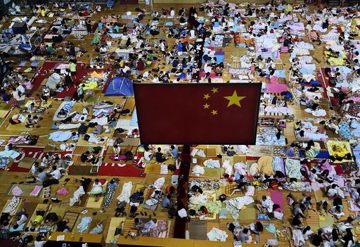 Students prepare to sleep on mats laid out on the floor under a Chinese national flag inside a gymnasium at the Huazhong Normal University in Wuhan, China
