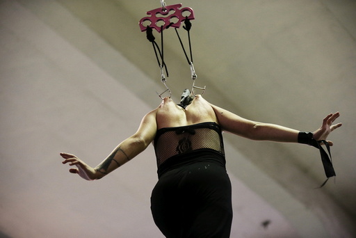 A woman hangs on hooks pierced into her skin during the latin america convention of tattoo and suspension in Valparaiso city