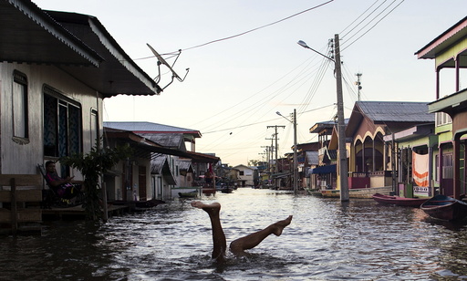 A child jokes in a street flooded by the rising Rio Solimoes, one of the two main branches of the Amazon River, in Anama