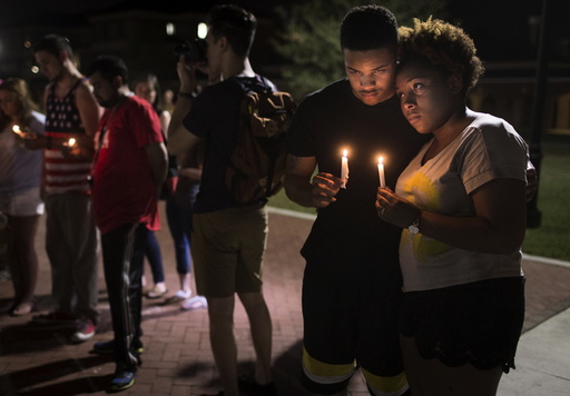 Sheldon Gilton and Brea Butler hold candles during a candlelight vigil for victims of the Thursday night shooting at a movie theater in Lafayette