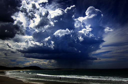 A giant storm cloud can be seen in the sky above swimmers near Mollymook Beach, south of Sydney