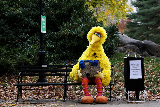 A man dressed as the Sesame Street character Big Bird sits on a bench waiting to take pictures with people walking through Central Park in New York