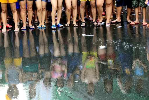 Residents are reflected on the wet street as they join in a water-splashing frenzy to honor their patron Saint John the Baptist's Feast Day in San Juan