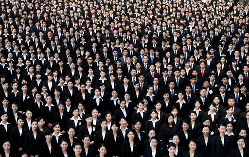 Newly-hired employees of JAL group pose for photos during an initiation ceremony at a hangar of Haneda airport in Tokyo