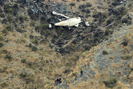 Rescue workers survey the site of a plane crashed a day earlier near the village of Saddha Batolni, near Abbotabad, Pakistan