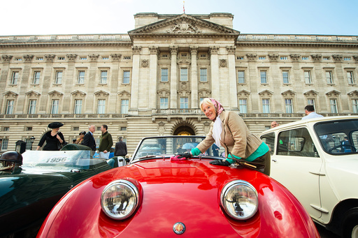 Carole Clark polishes a 1958 Austin Healey Sprite mk1, part of a display of 90 historic British-built motor vehicles standing on the forecourt of Buckingham Palace commemorating Queen Elizabeth's 90th birthday, in London