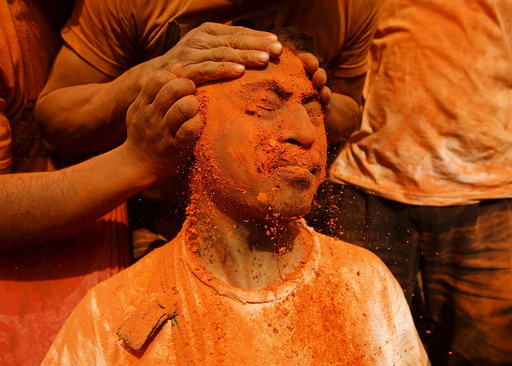 A devotee is smeared with a vermillion powder while celebrating Sindoor Jatra vermillion powder festival at Thimi
