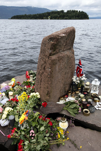 Flowers and candles are seen on the shore in front of Utoeya island northwest of Oslo
