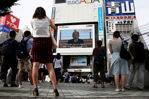 People watch a large screen showing Japanese Emperor Akihito's video address in Tokyo