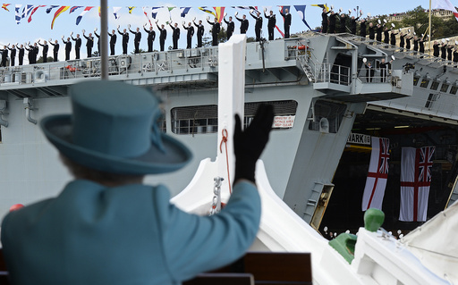 Britain's Queen Elizabeth waves to British Royal Navy crew members performing a salute on the HMS Bulwark amphibious assault ship during a State Visit and Commonwealth Heads of Government Meeting in Valletta
