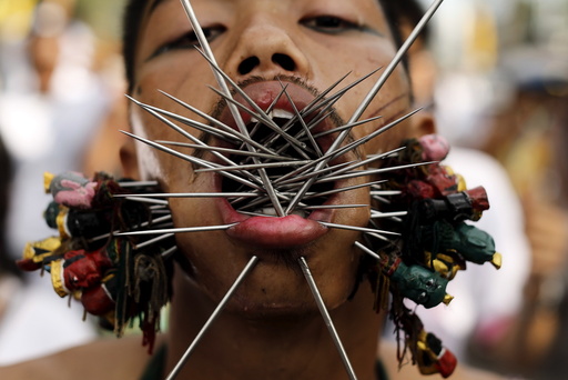 A devotee of the Chinese Samkong Shrine walks with spikes pierced through his cheeks during a procession celebrating the annual vegetarian festival in Phuket, Thailand
