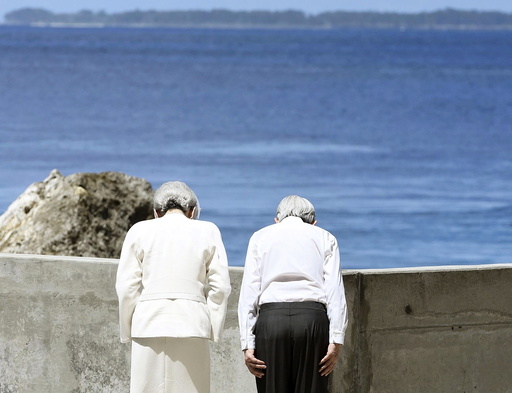Japan's Emperor Akihito and Empress Michiko bow towards Angaur Island after they offered flowers to the cenotaph for war dead in the western Pacific area, on Palau's Peleliu Island