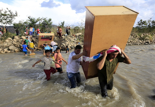 People carry their belongings while crossing the Tachira river border with Venezuela into Colombia near Villa del Rosario village