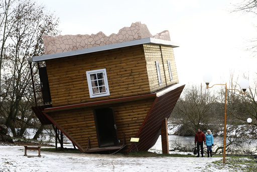 People walk outside an upside-down house in a tourist complex, near the village of Dukora