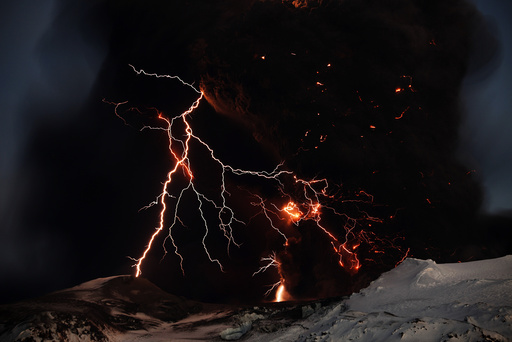 Lightning streaks across the sky as lava flows from a volcano in Eyjafjallajokul