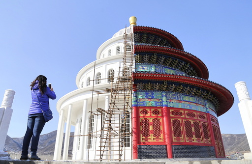 Woman takes pictures at a building, which is made by half of a replica of the Qinian Hall of the Temple of the Heaven and half of a western building, at a studio for productions of films and television shows on the outskirts of Shijiazhuang