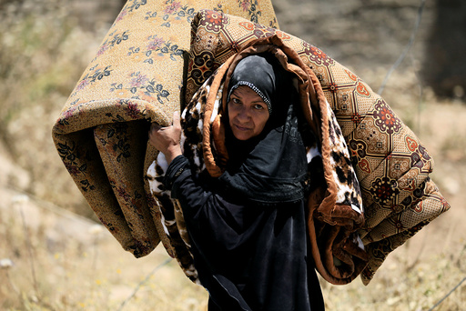 A displaced Iraqi woman who fled her home carries a mattress in al-Zanjili neighbourhood
