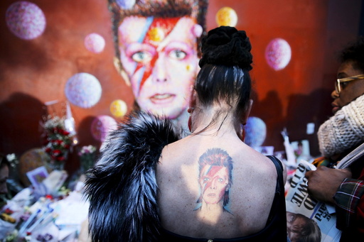 A woman with a Ziggy Stardust tattoo visits a mural of David Bowie in Brixton, south London