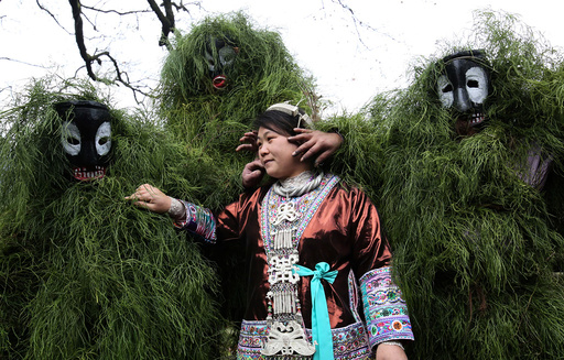 Ethnic Miao men wearing traditional masks smear dust on a woman's face to wish her good luck during a local celebration event for Lunar New Year in Liuzhou