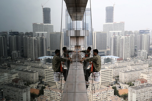Labourers clean the glass windows outside a 30-floor business building in Qingdao