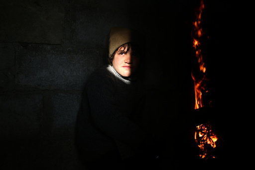 A boy stands near a fire in the rebel held besieged Douma neighbourhood of Damascus
