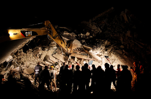 Rescuers work in the night at a collapsed house following an earthquake in Pescara del Tronto