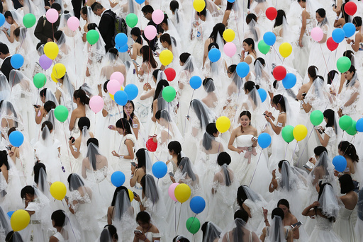 Women in wedding dresses hold balloons at a wedding dress market during an event attempting to break the Guinness world record for a gathering with the most people dressed as brides, in Suzhou