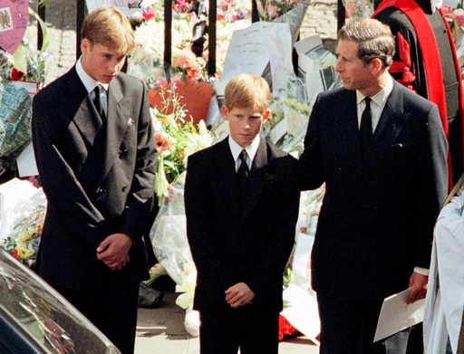 Prince Charles touches the shoulder of his son Harry as his other son Prince William watches the hea..