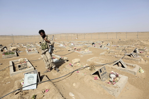An army soldier stands next to graves of Houthi fighters in the historical town of Baraqish in Yemen's al-Jawf province