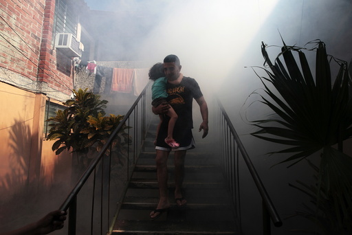 A man walks away from his home with his son as health workers fumigates the Altos del Cerro neighbourhood as part of preventive measures against the Zika virus and other mosquito-borne diseases in Soyapango, El Salvador