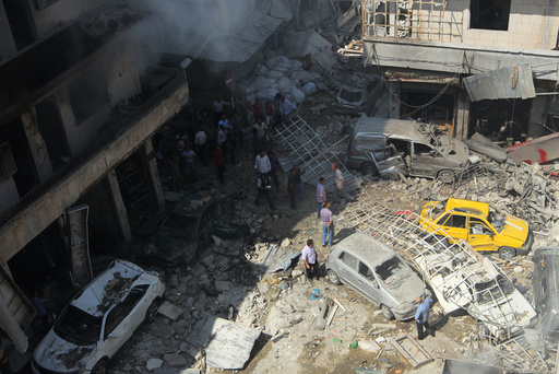 Residents inspect a damaged site after airstrikes on a market in the rebel controlled city of Idlib