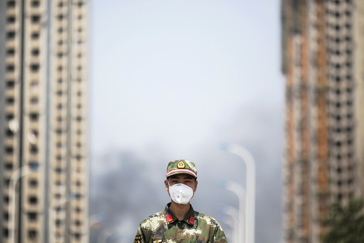 A paramilitary policeman wears a mask as he blocks the road leading to evacuated residential area and the explosion site in Binhai new district in Tianjin