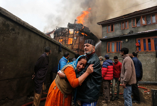 A woman is consoled by her relative as she mourns after seeing her house getting burned during a fire that broke out in a residential locality in Srinagar