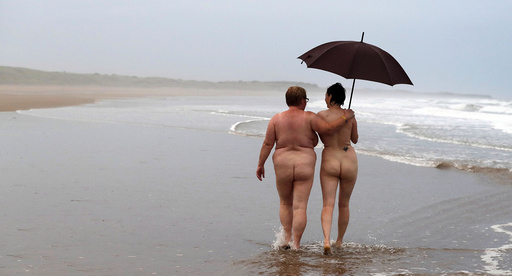 Two women walk along the beach after taking part in the annual North East Skinny Dip at Druridge Bay