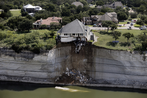 Crews prepare to set a house on fire, days after part of the ground it was resting on collapsed into Lake Whitney