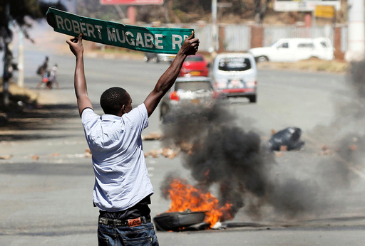 A man carries a street sign as opposition party supporters clash with police in Harare