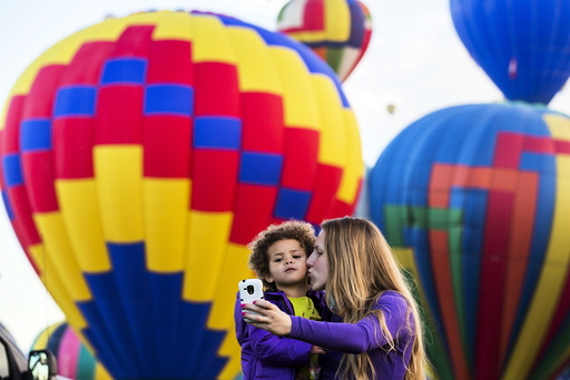 A woman and child take a photograph as hot air balloons lift off during the 2015 Albuquerque International Balloon Fiesta in Albuquerque, New Mexico