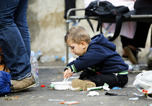 A migrant boy eats on the ground at the check point Heiligenkreuz