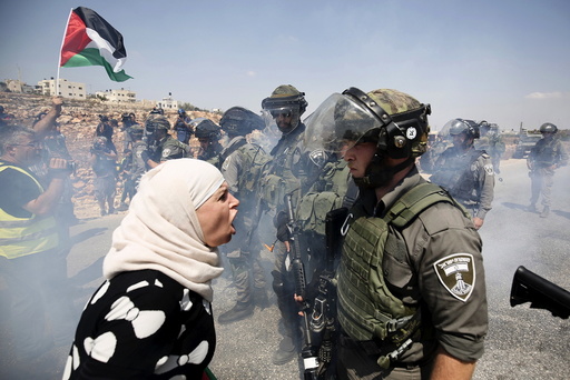 A Palestinian woman argues with an Israeli border policeman during a protest against Jewish settlements in the West Bank village of Nabi Saleh, near Ramallah