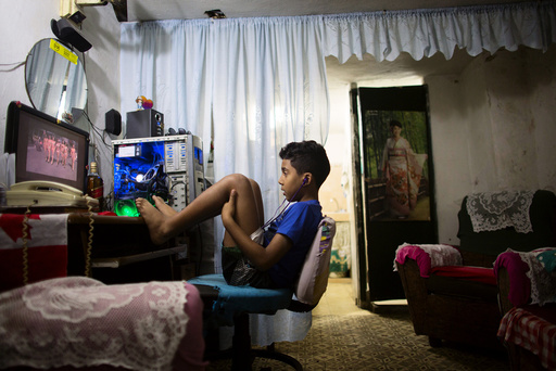 A boy watches a recorded TV show through the screen of a computer at the living room of his home in downtown Havana