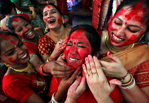 Hindu women apply sindhur, or vermillion powder, on the face of a woman after worshipping the idol of the Hindu goddess Durga on the last day of the Durga Puja festival in Chandigarh